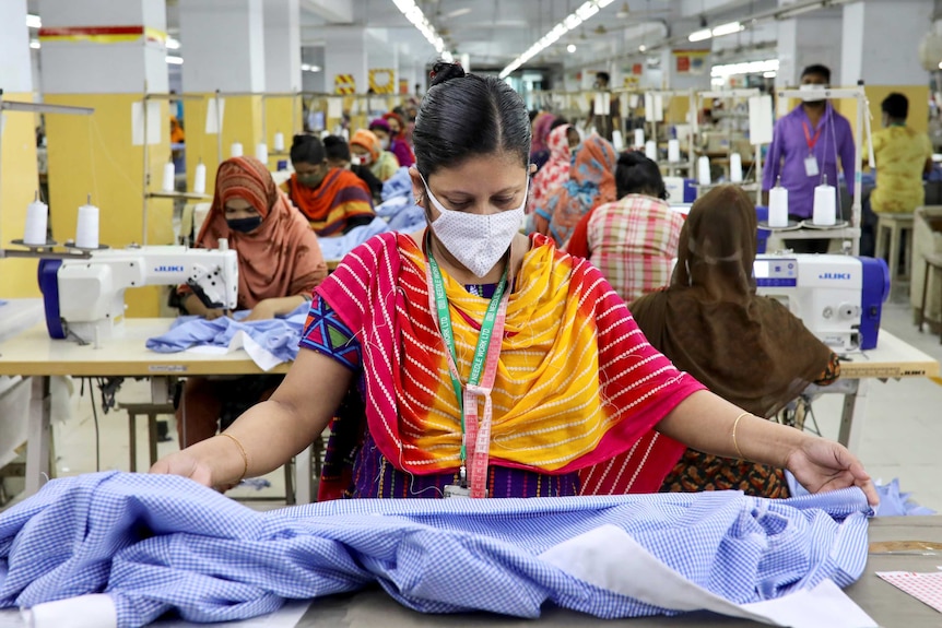 A woman in a face mask looking at fabric in a garment factory