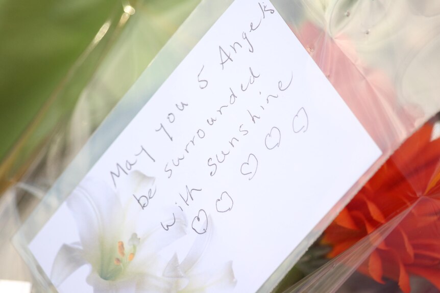 A note on a floral tribute reads: May you angels be surrounded with sunshine