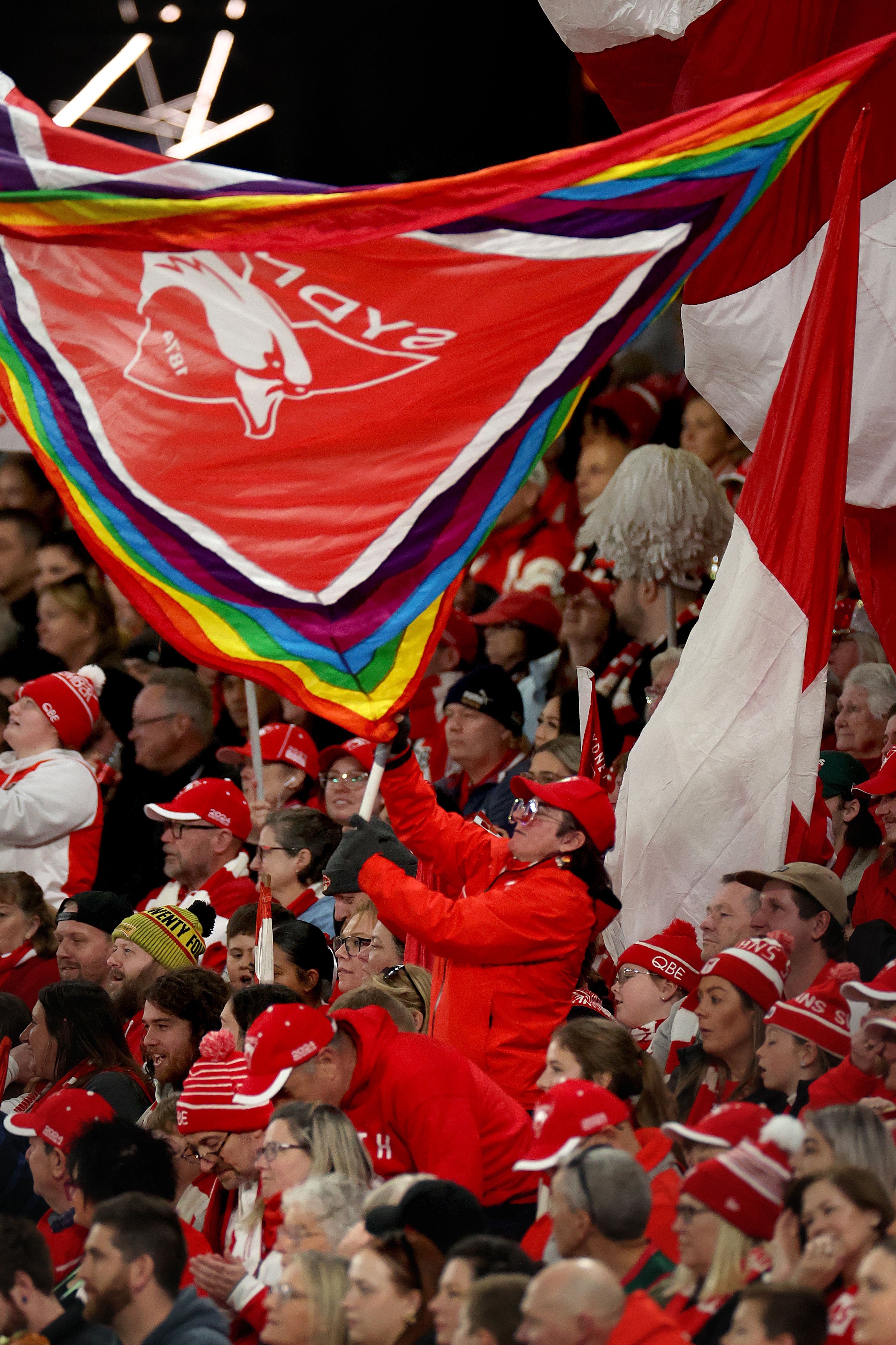 Sydney Swans crowd wave pride flags.