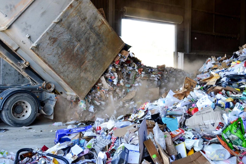 A truck scoops up a large amount of recycling and garbage.