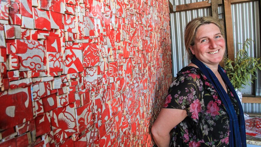 Woman stands in front of artwork made up of multiple blocks
