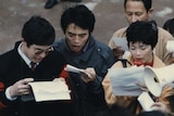 You see a scanned film photo showing a group of young Chines men and women holding paper and megaphones.
