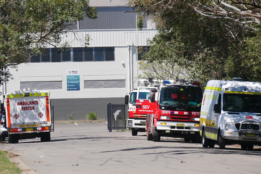 The exterior of a warehouse with emergency vehicles parked out the front