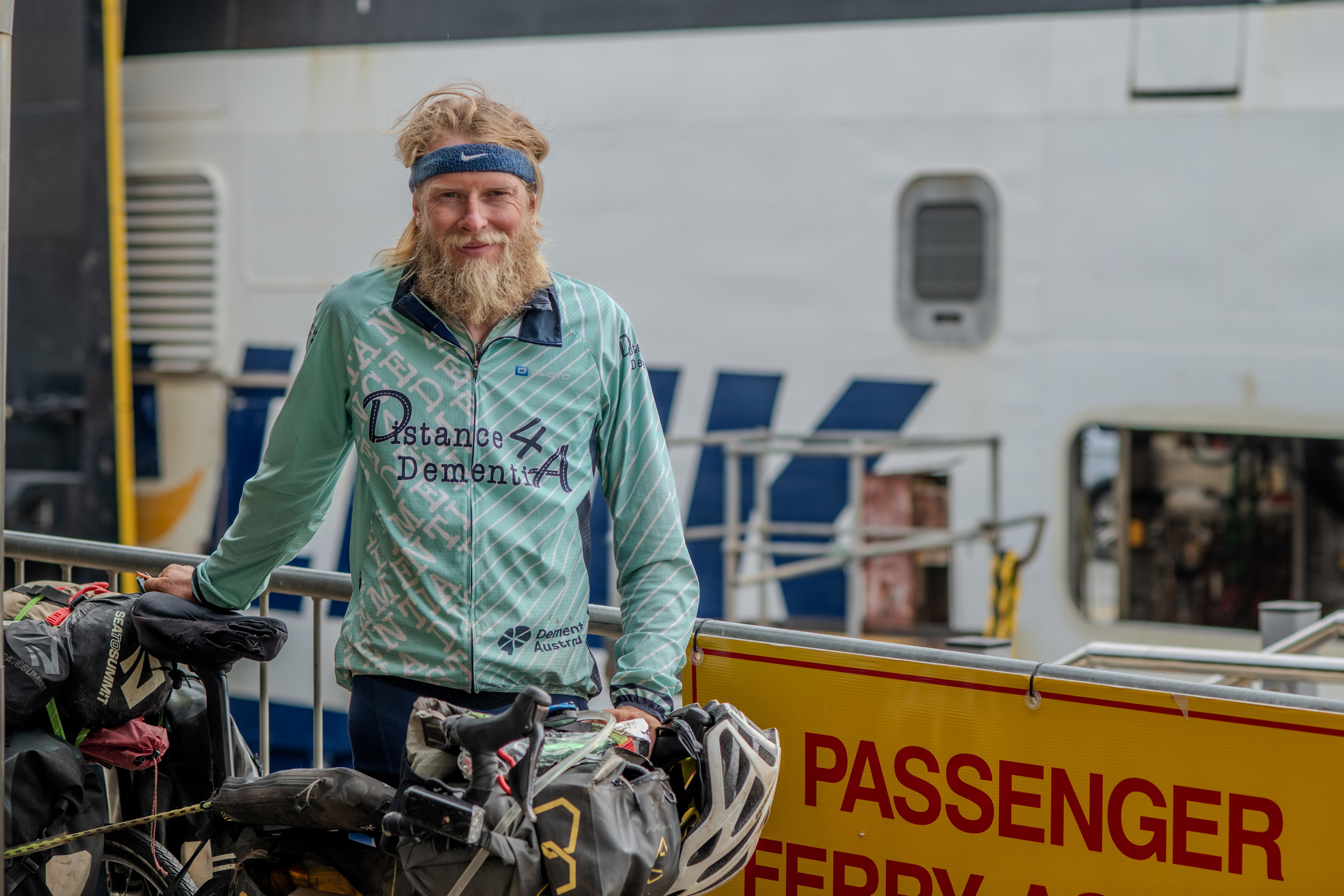 A man with a bicycle and a Distance 4 Dementia shirt at the ferry terminal in Cape Jarvis.