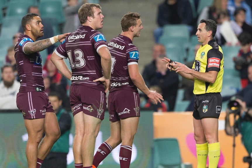 Daly Cherr-Evans speaks with referee Gerard Sutton, as his Manly teammates look on.