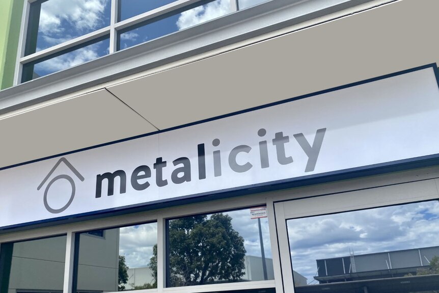 Un letrero de oficina en el frente del edificio de la empresa de exploración de oro Metalicity.  