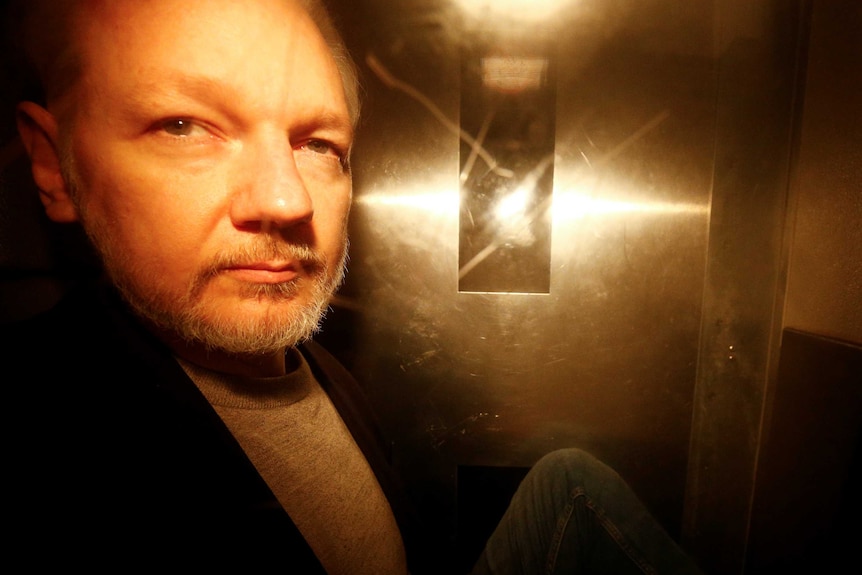 A photo of Julian Assange taken through the window of a police van.