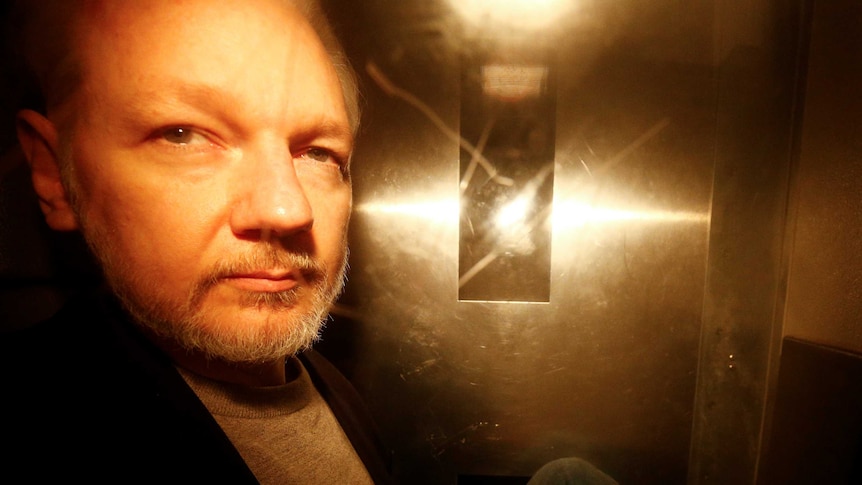 A photo of Julian Assange taken through the window of a police van