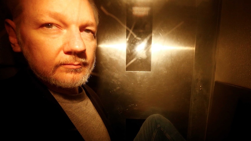 A photo of Julian Assange taken through the window of a police van