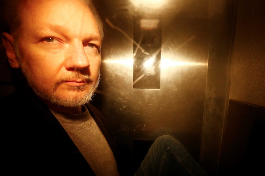 Julian Assange seen through the window of a police van.