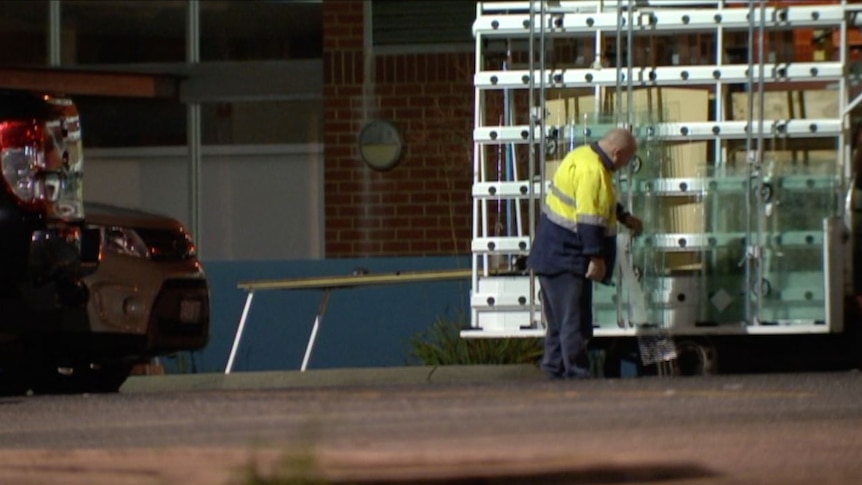 A glazier examines glass panels outside a prison at night.