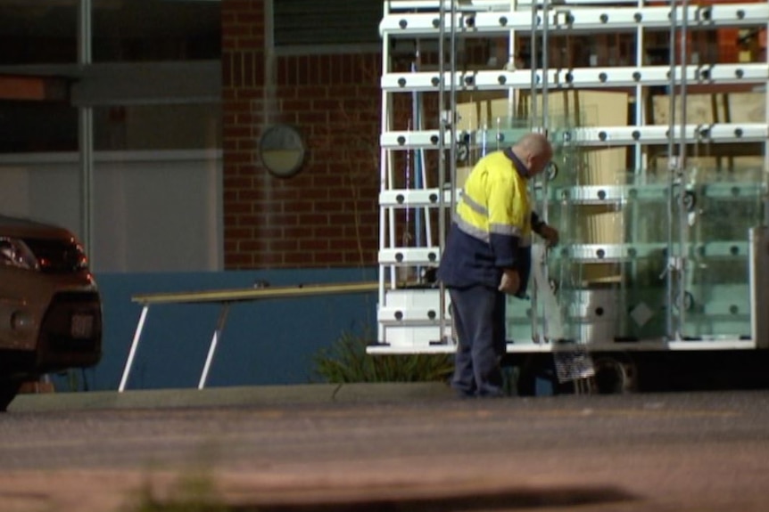 A glazier examines glass panels outside a prison at night.