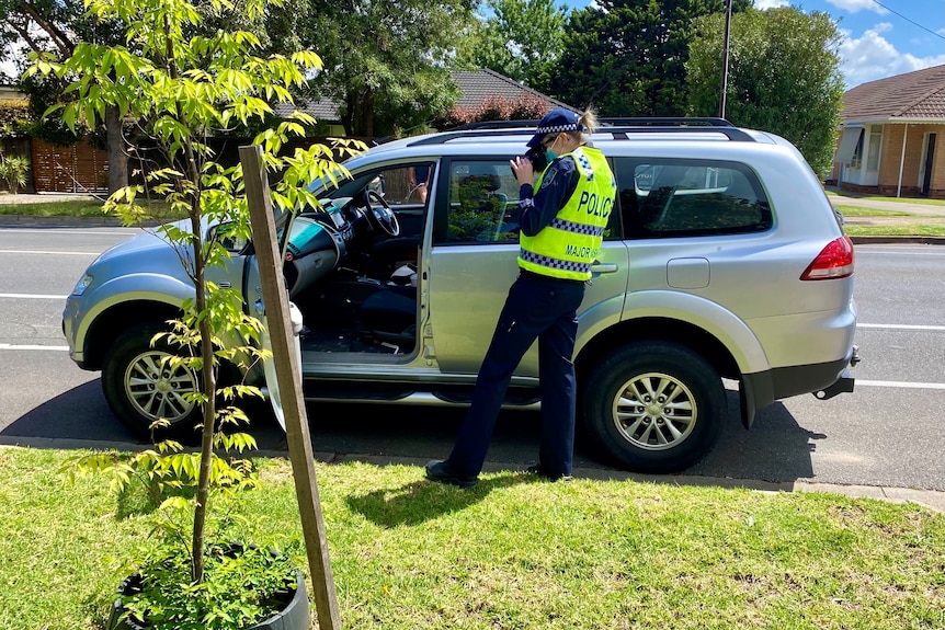 A police officer takes a photo of a car on The Parade at Rosslyn Park.