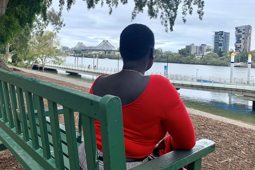 A woman seen from behind staring at the Brisbane River, the Story Bridge visible in the distance