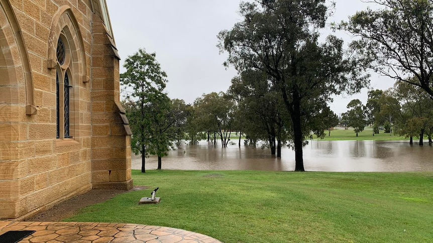 A river which has burst its banks near a sandstone building.