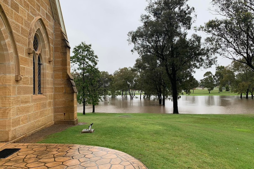 A river which has burst its banks near a sandstone building.