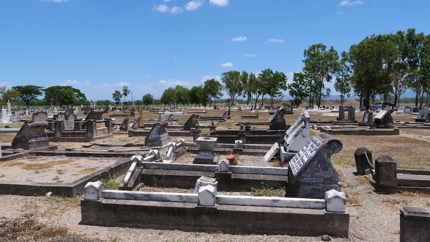 Looking down a line of old, rundown 19th century graves in full sun at Proserpine Cemetery.