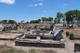 Looking down a line of old, rundown 19th century graves in full sun at Proserpine Cemetery.