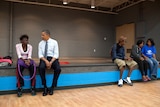 Barack Obama sits and speaks to a young girl. 