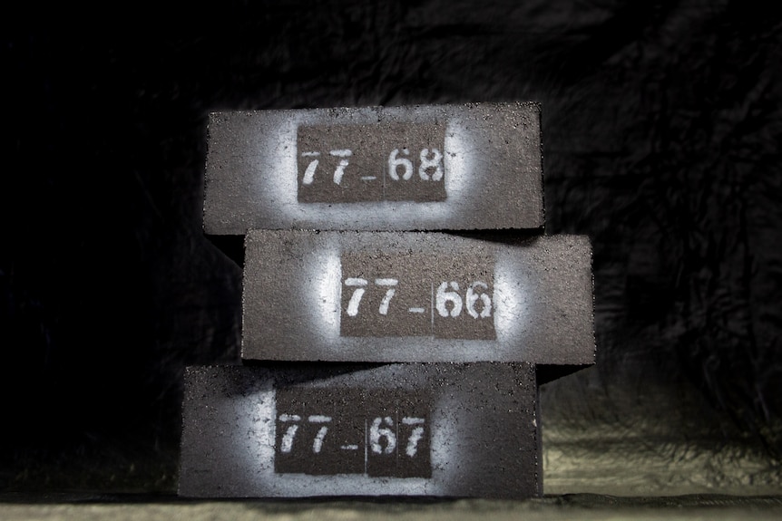 A stack of dark-coloured blocks with numbers sprayed on the side.