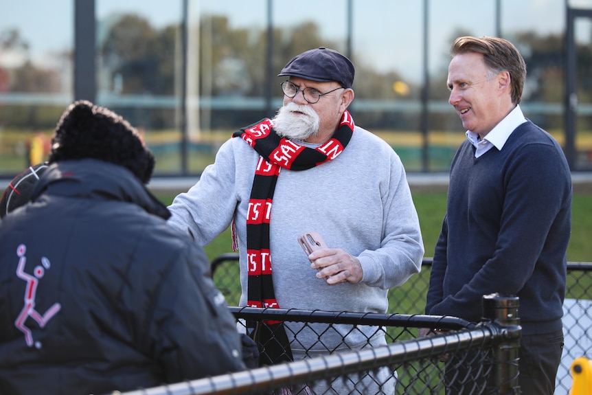 Robert Muir and Matt Finnis speak to fans at a club training session.