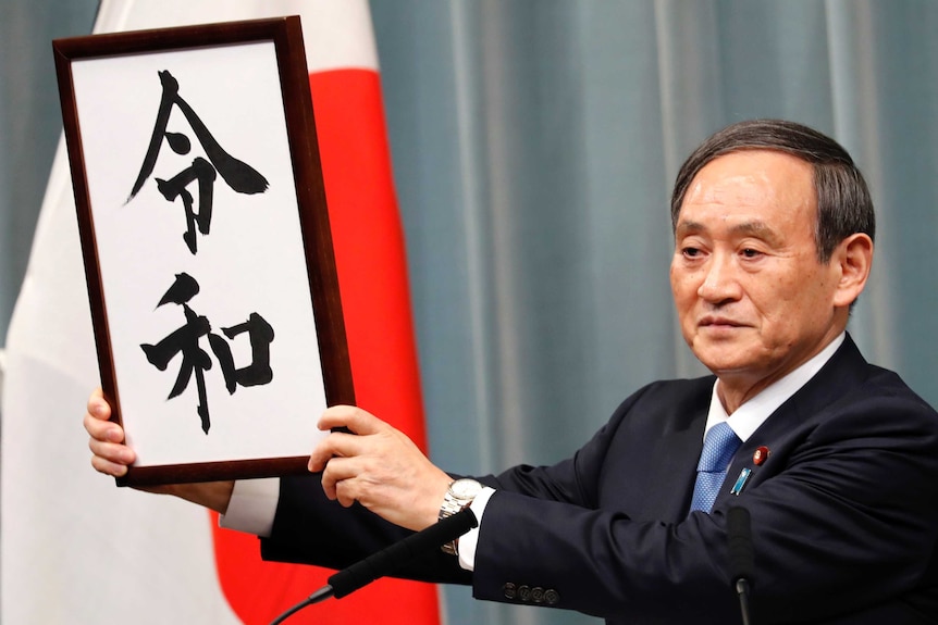 Japan's Chief Cabinet Secretary Yoshihide Suga holds a sign to unveil the name of new era "Reiwa".
