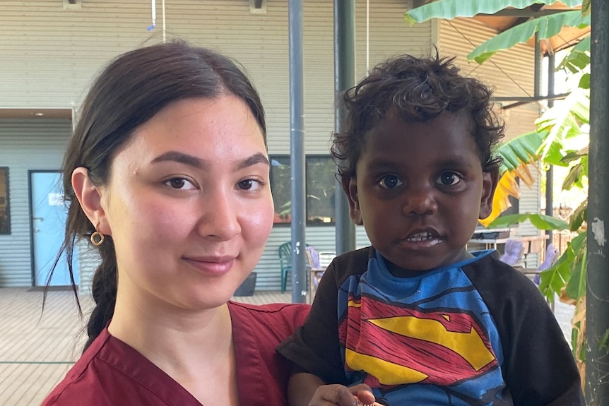 a nurse holds an aboriginal toddler in a remote medical clinic