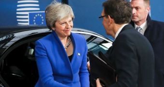 Theresa May shakes hands with a man that has his back to the camera.