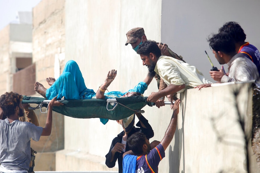 Volunteers carry an injured person at the site of a plane crash in Karachi, Pakistan.