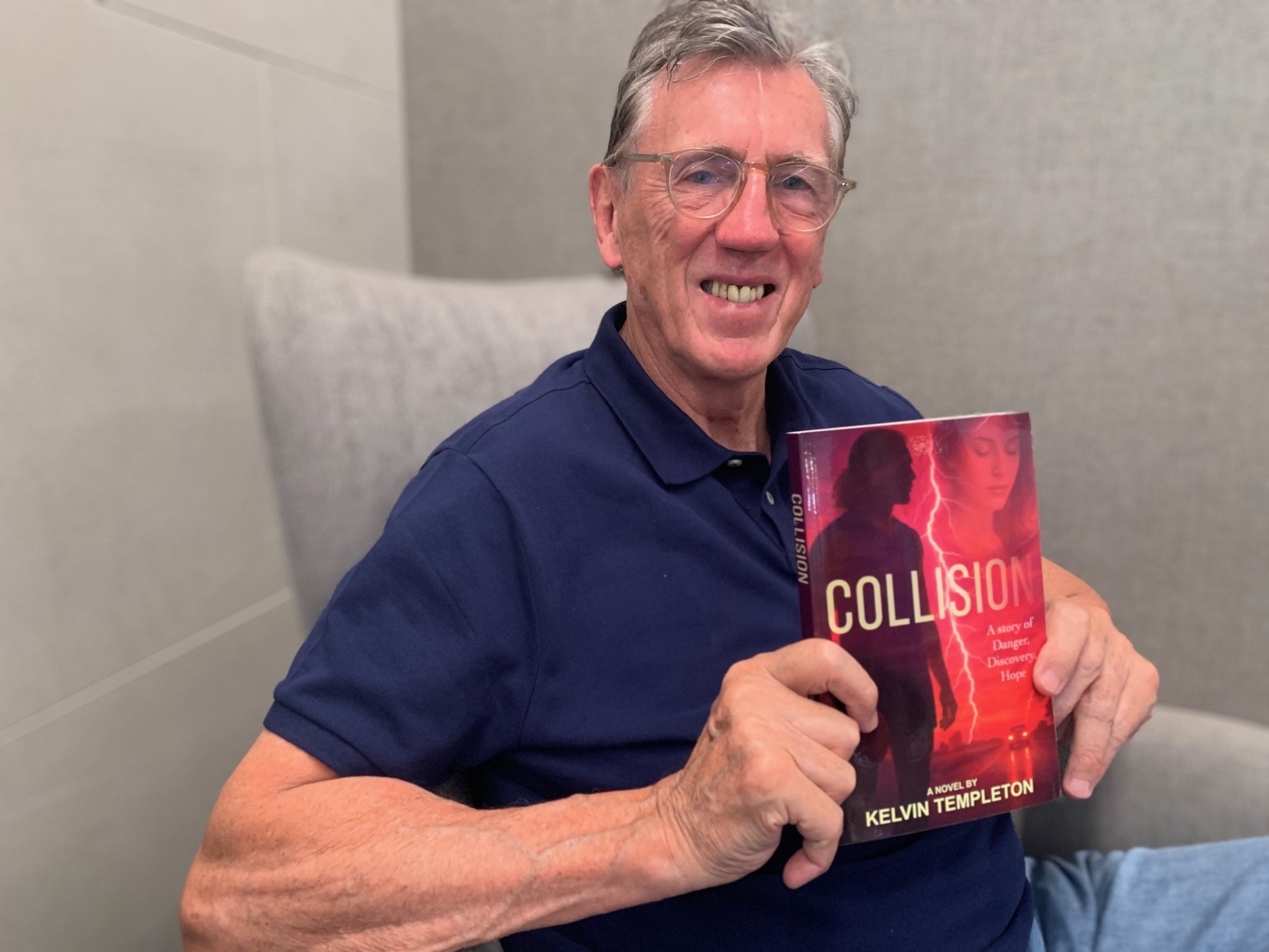 Kelvin Templeton está sentado sorrindo e segurando um livro.