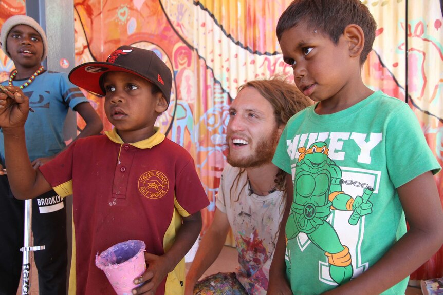 Max Frieder with Indigenous kids in front of their mural in Alice Springs
