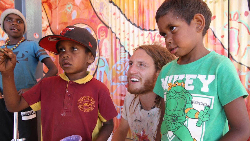 Max Frieder with Indigenous kids in front of their mural in Alice Springs