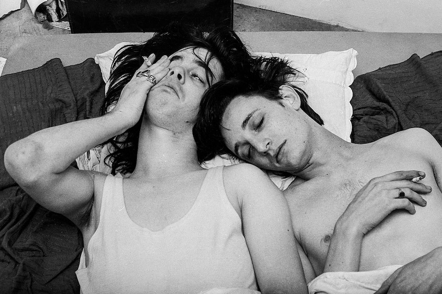 A black and white photo of Nick Cave and Rowland Howard very young, napping on each other on the ground