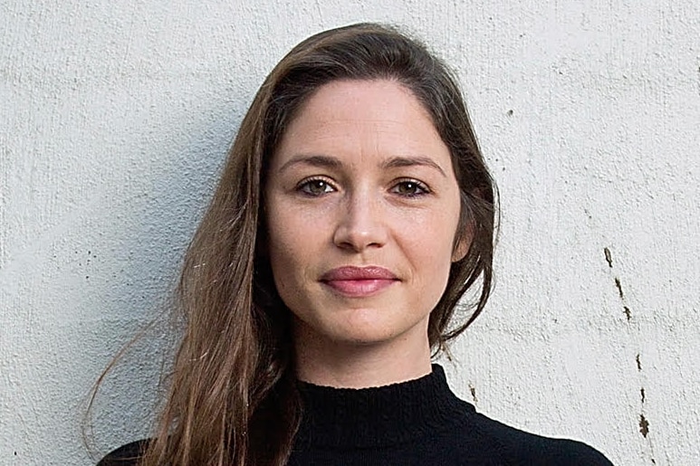 A woman in a black jumper with long brown hair.