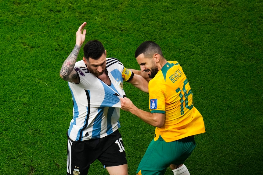 Soceroos' Aziz Behich tugs at the jersey of Argentina's Lionel Messi during their Qatar World Cup match.