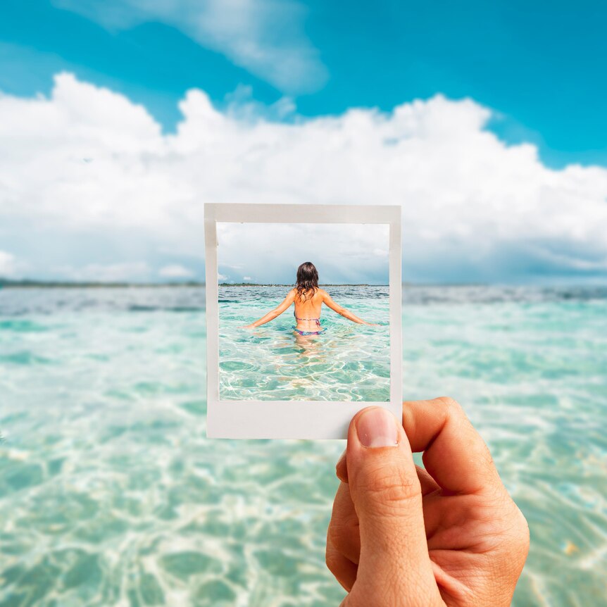 Woman seen from behind in the ocean - seen through a cut-out polaroid frame.