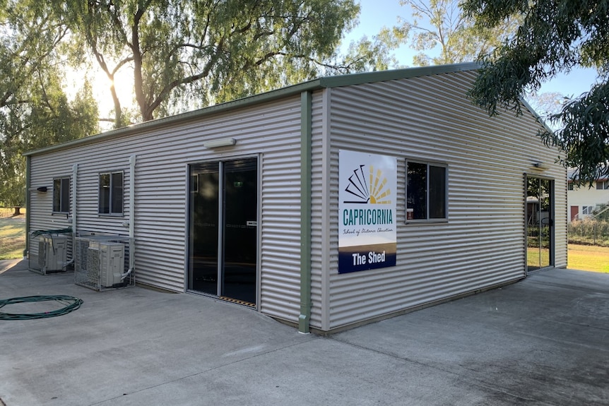 A steel shed on cement, there are trees in the background