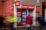 Flight Centre store front, with a laneway next to it, as people walk past.
