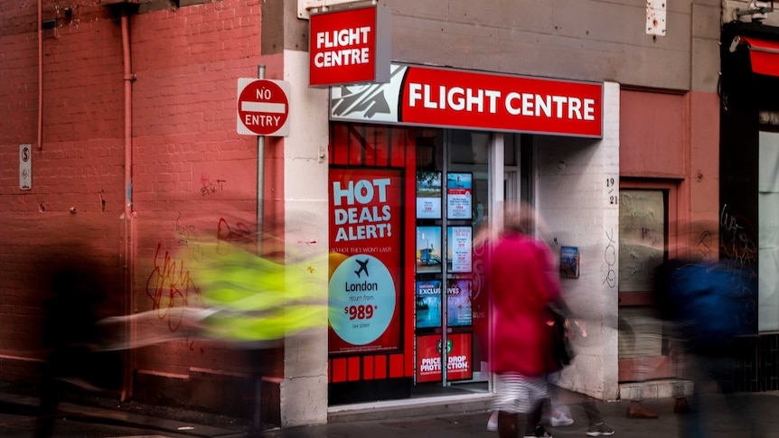 Flight Centre store front, with a laneway next to it, as people walk past.