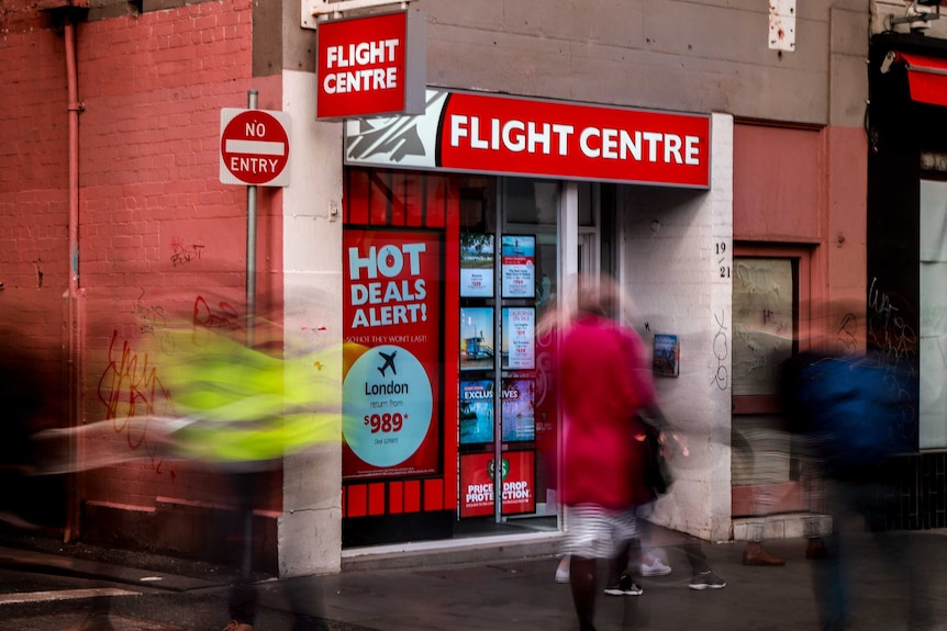 Flight Centre store front, with a laneway next to it, as people walk past.