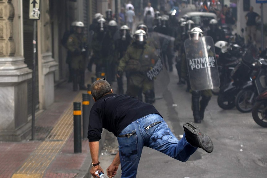 Protester throws rock at Greek police