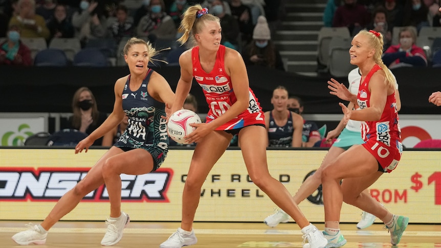 A NSW Swifts Super Netball player holds the ball in two hands against the Melbourne Vixens.