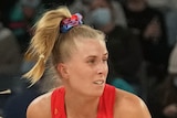 A NSW Swifts Super Netball player holds the ball in two hands against the Melbourne Vixens.