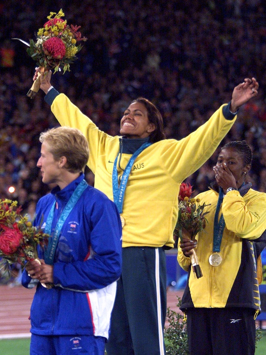 Australia's Cathy Freeman (C) waves to the crowd from the medal winners podium at the Sydney Olympic Games, September 25, 2000.