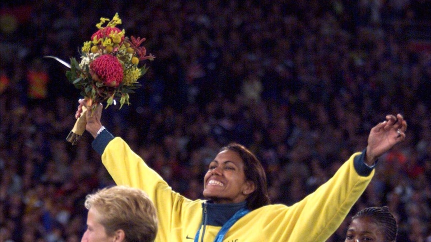Australia's Cathy Freeman (C) waves to the crowd from the medal winners podium at the Sydney Olympic Games, September 25, 2000.