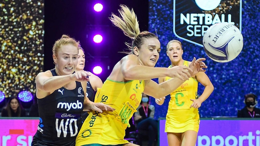 A netball defender reaches out as an attacker loses control of the ball in a Test match.