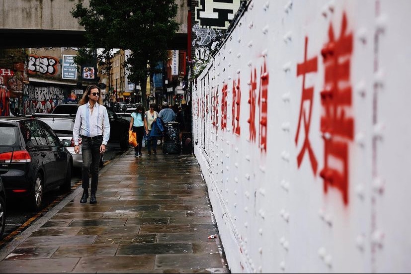 一名男子走过印有红字的砖墙