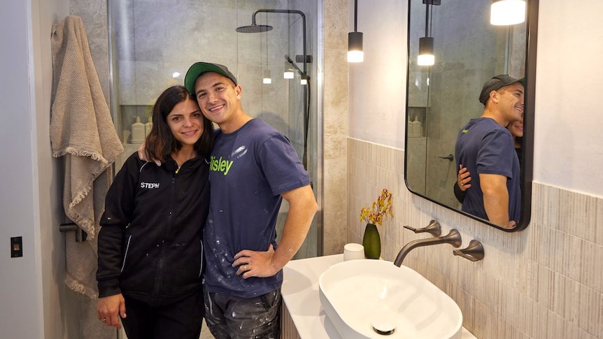 A man and a woman hug while standing in a bathroom.