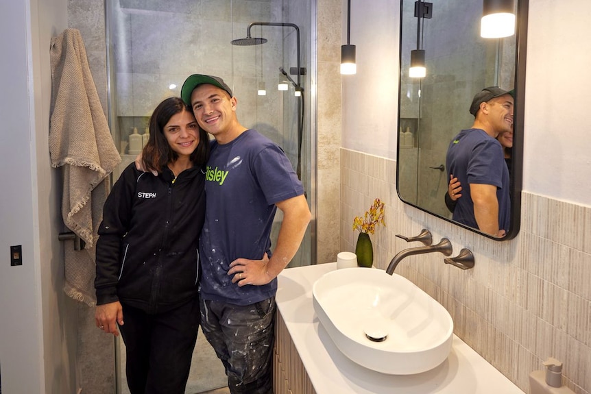 A man and a woman hug while standing in a bathroom.