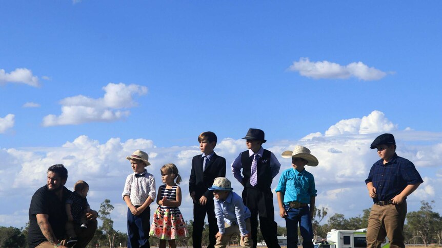 Children standing on a hill at the Barcaldine turf track in their best races outfits